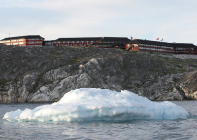 Hotel Arctic in Groenland vom Wasser aus mit Eisberg und Felsen