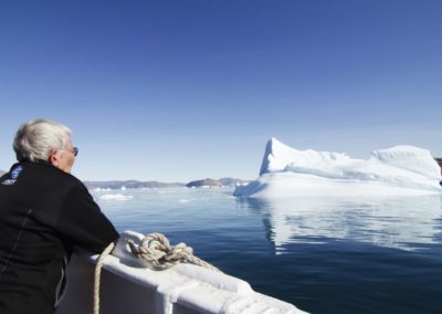 Eine Expeditionsteilnehmerin auf dem Deck der MS Balto bestaunt die Landschaft Westgrönlands